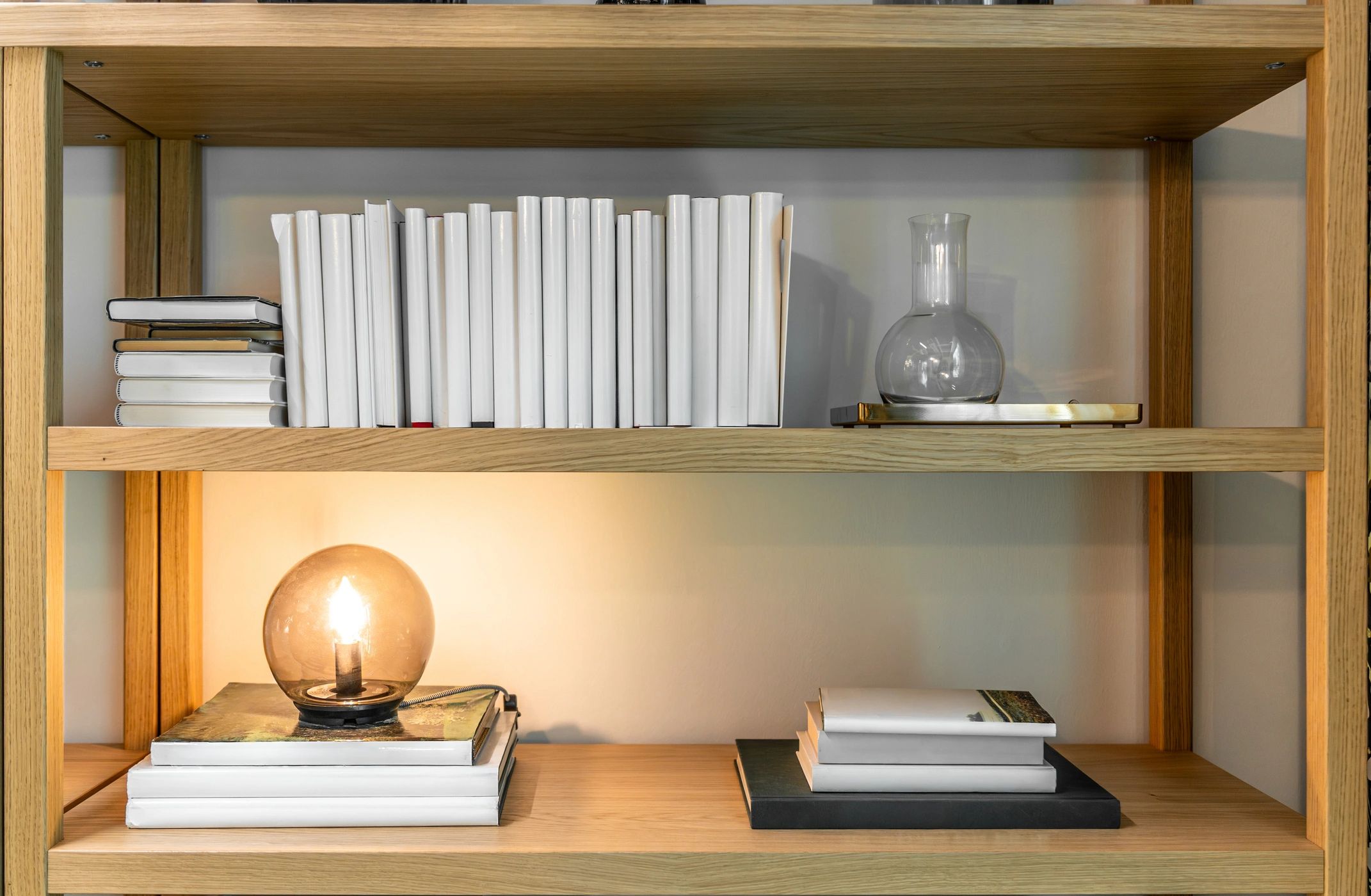Warm bookshelf styling with books and lamp